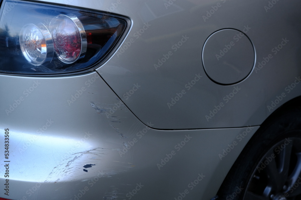 Scratched back bumper on the grey metallic car. Closeup image of damaged back bumper on the car. Photo for the insurance company of a scratched car.