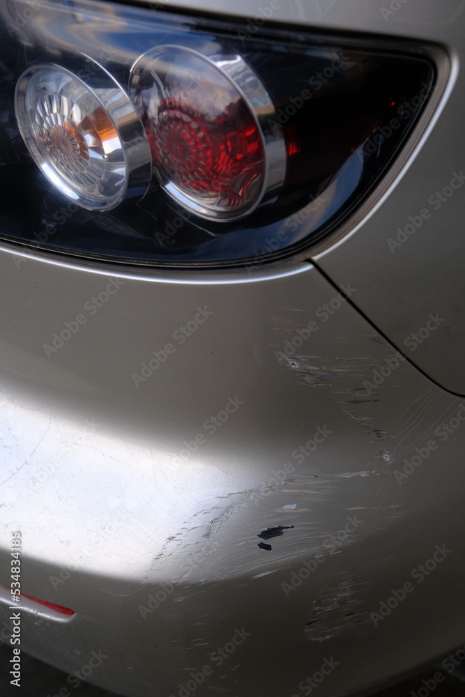 Scratched back bumper on the grey metallic car. Closeup image of damaged back bumper on the car. Photo for the insurance company of a scratched car.