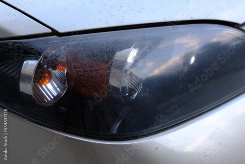 Close-up head light of car with scratches and need to polish in service. Polish car concept. Car lights service photo