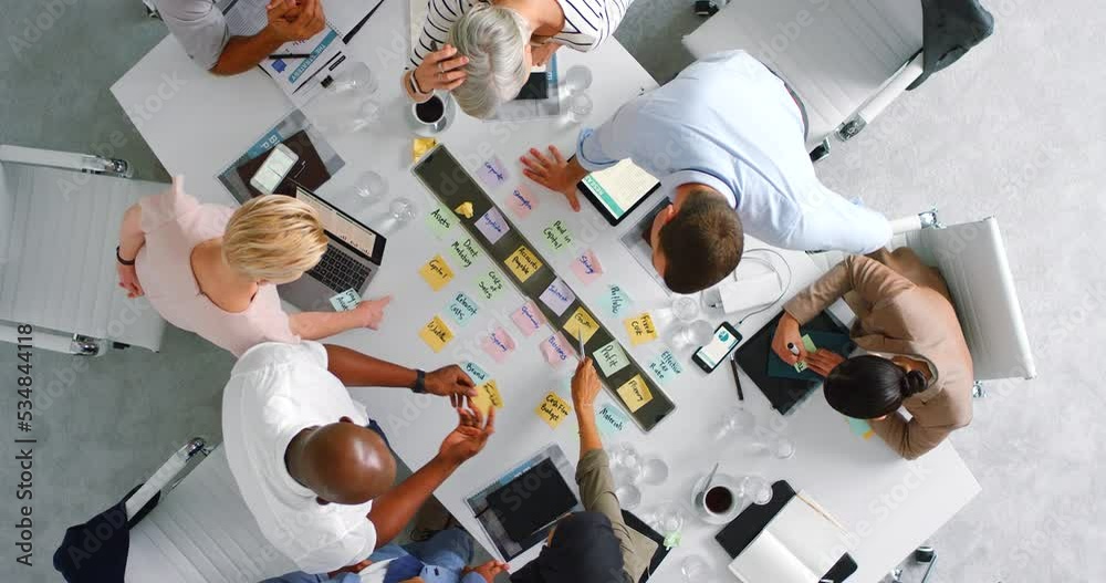 Strategy, planning and business meeting with sticky notes from above with employees in conference, office or boardroom. Post it, brainstorming, planning with business people for support and idea