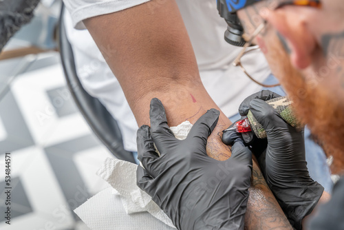 Tatoueur en train de dessiner à l'aiguille sur la peau d'un bras