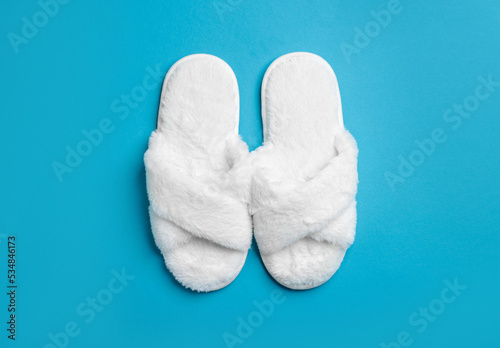 Pair of soft fluffy slippers on blue background, top view