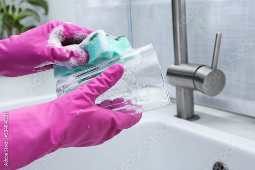 Fototapeta Naklejka Na Ścianę i Meble -  Woman washing glass with sponge above sink in kitchen, closeup