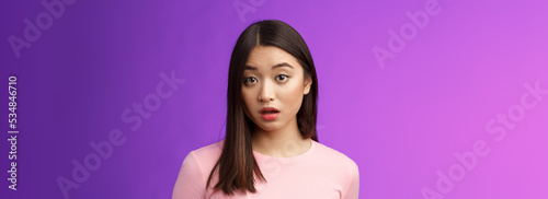 Close-up confused shocked cute young silly asian girl hear strange accusations open mouth gasping stunned, look speechless and puzzled, did not expect such behaviour, purple background