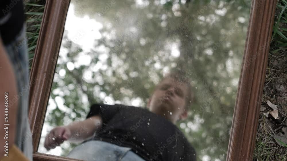 A young high school aged teen boy looking serious, angry and sad looks at his reflection in a mirror. A young high school aged teen boy looking serious, angry and sad looks at his reflection in a mirror.