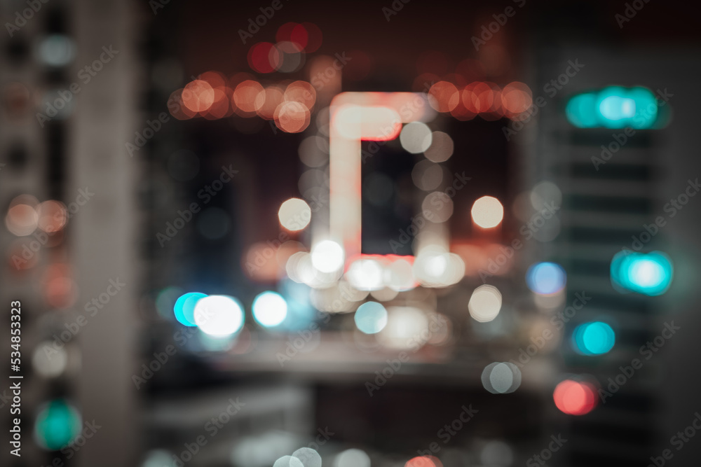 Blurred bokeh city lights background with reddish and teal defocused neon illumination Blurred bokeh city lights background with reddish and teal defocused neon illumination