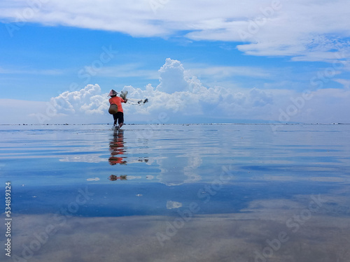 a fisherman catching fish with net on the beach