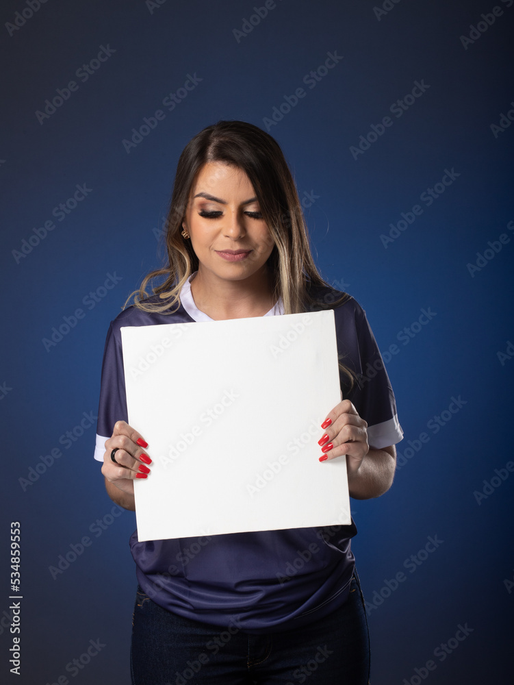 woman soccer fan cheering for her favorite club and team. world cup blue background. Holding White Blank Card. woman soccer fan cheering for her favorite club and team. world cup blue background. Holding White Blank Card.