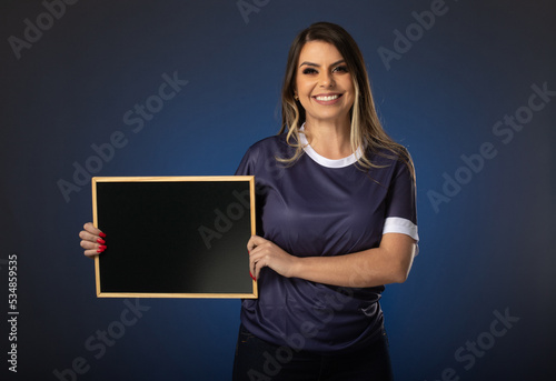 woman soccer fan cheering for her favorite club and team. world cup blue background. Holding a blackboard.