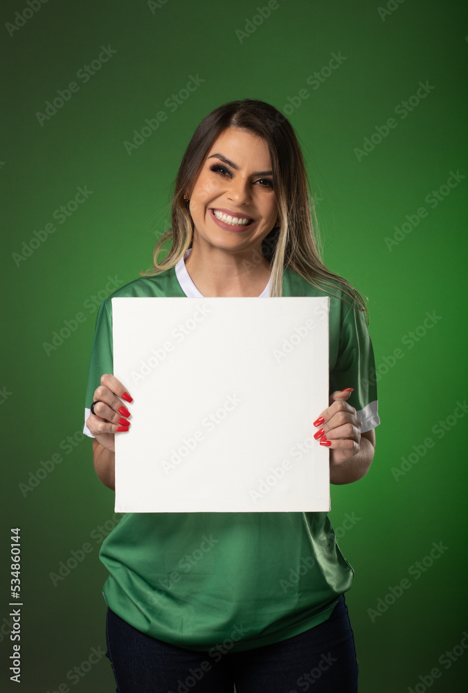 woman soccer fan cheering for her favorite club and team. world cup green background. Holding White Blank Card. woman soccer fan cheering for her favorite club and team. world cup green background. Holding White Blank Card.