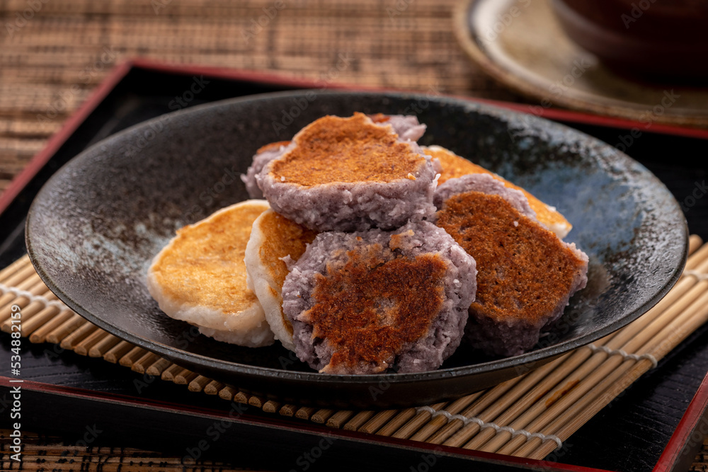 Babin, a simple chewy Thai dessert simply made of glutinous rice flour, coconut flesh, palm sugar, coconut milk and salt and pan grilled on a flat pan. Dark tone.