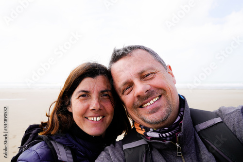 cheerful happy tourist couple taking selfie in vacation on sand beach sea