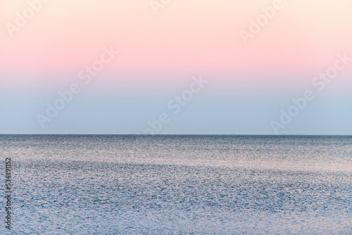 Atmospheric romantic pink red sea sunset sky above blue quiet water, minimalistic peaceful seascape, beautiful background copy space. Pinkish sky above Azov sea horizon, Rostov on Don region in Russia photo