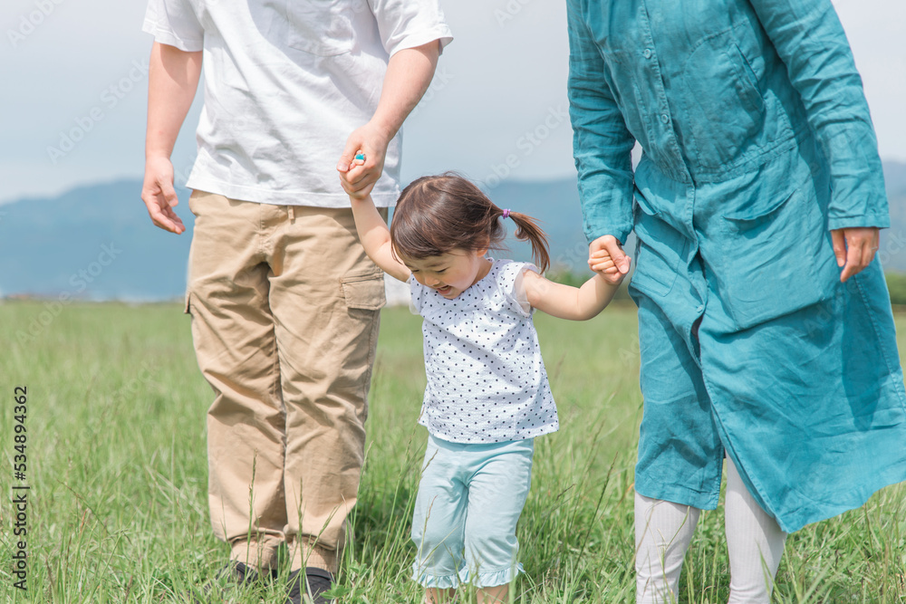 両親と手を繋いで歩く笑顔の子供
両親と手を繋いで歩く笑顔の子供