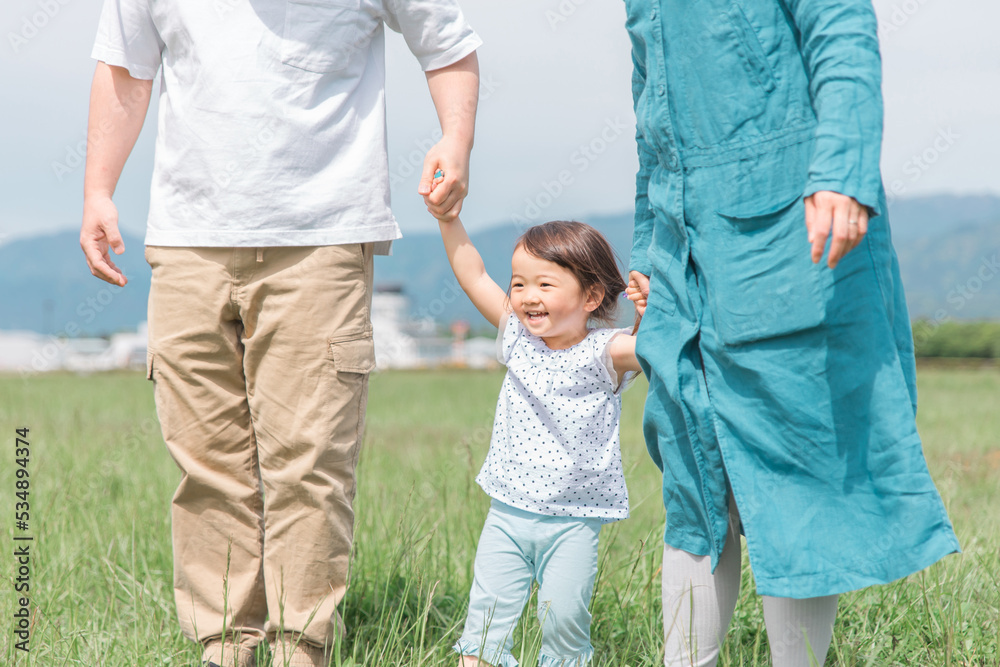 両親と手を繋いで歩く笑顔の子供
両親と手を繋いで歩く笑顔の子供