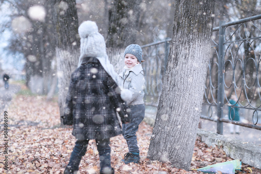 Naklejka premium Kids walk in the park first snow