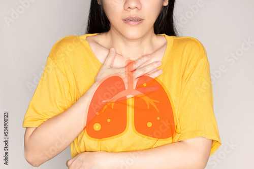 Asian beautiful woman sitting in living room are cough and using hand touch her chest . Healthcare concept. photo