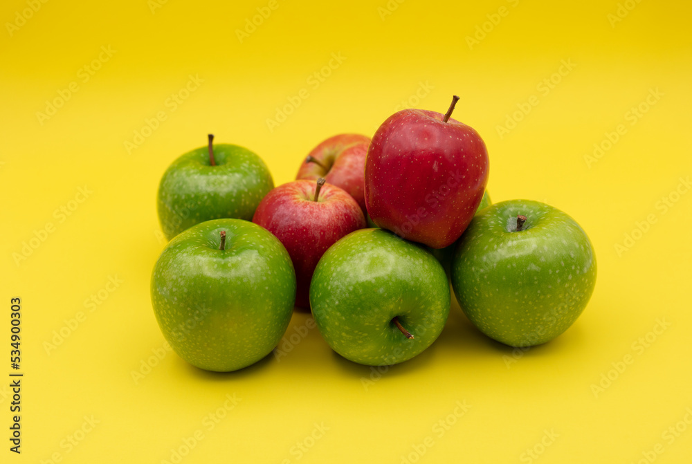 green apples and red apples on yellow backround green apples and red apples on yellow backround