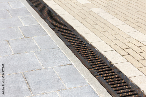 Drainage Grid on Cobblestone. Gutter Floor, Drain Grate for Rain Water on Sidewalk.