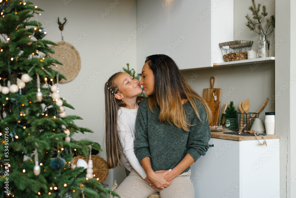 Happy family mom and daughter have fun preparing for Christmas and New Year in the kitchen near the Christmas tree