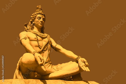 Lord Shiva sits near the Ganges River at the foot of the Himalayas in Rishikesh, India. Yoga and meditation concept. Beautiful big statue of meditating Shiva.  photo