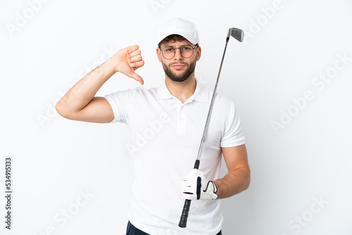 Handsome young man playing golf isolated on white background showing thumb down with negative expression