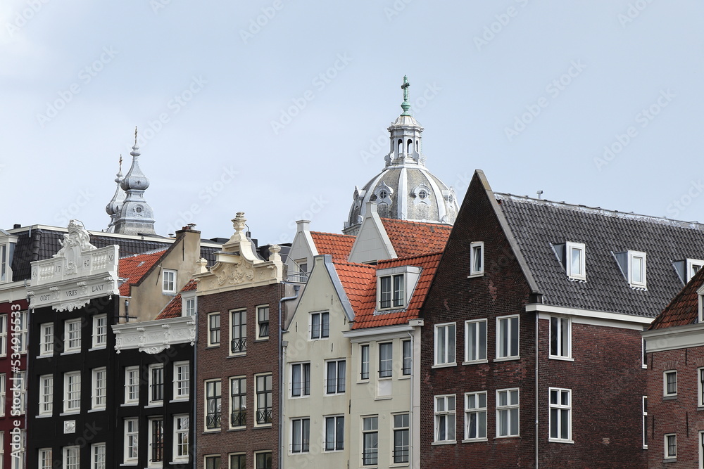 Amsterdam Damrak Canal Historic House Facades with Church Towers in the Background Close Up, Netherlands