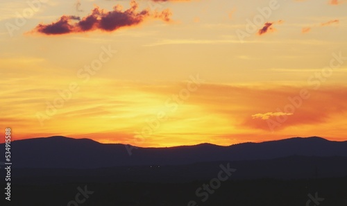 Atardecer en la Sierra de Guadarrama en Madrid, España. Cielo anaranjado con los últimos rayos de sol destacando la silueta de las montañas situadas al norte de Madrid.