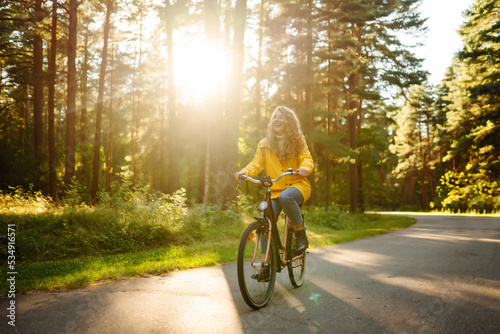 Fototapeta Naklejka Na Ścianę i Meble -  Beautiful happy woman in yellow coat riding bicycle in autumn park. Autumn fashion. Lifestyle. Relax, nature concept.