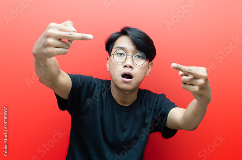 asian young man showing his middle finger as bad and anger expression isolated over red background