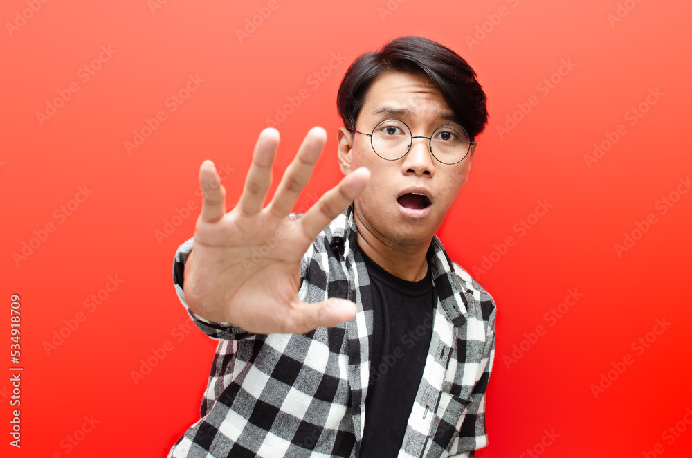 get away from me. asian man is scared and trying to defend by his hand. man refuse and reject something. asian man makes stop gesture. get away from me. asian man is scared and trying to defend by his hand. man refuse and reject something. asian man makes stop gesture.