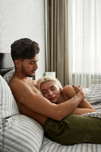 Girl sleep in embrace of boyfriend on bed at home