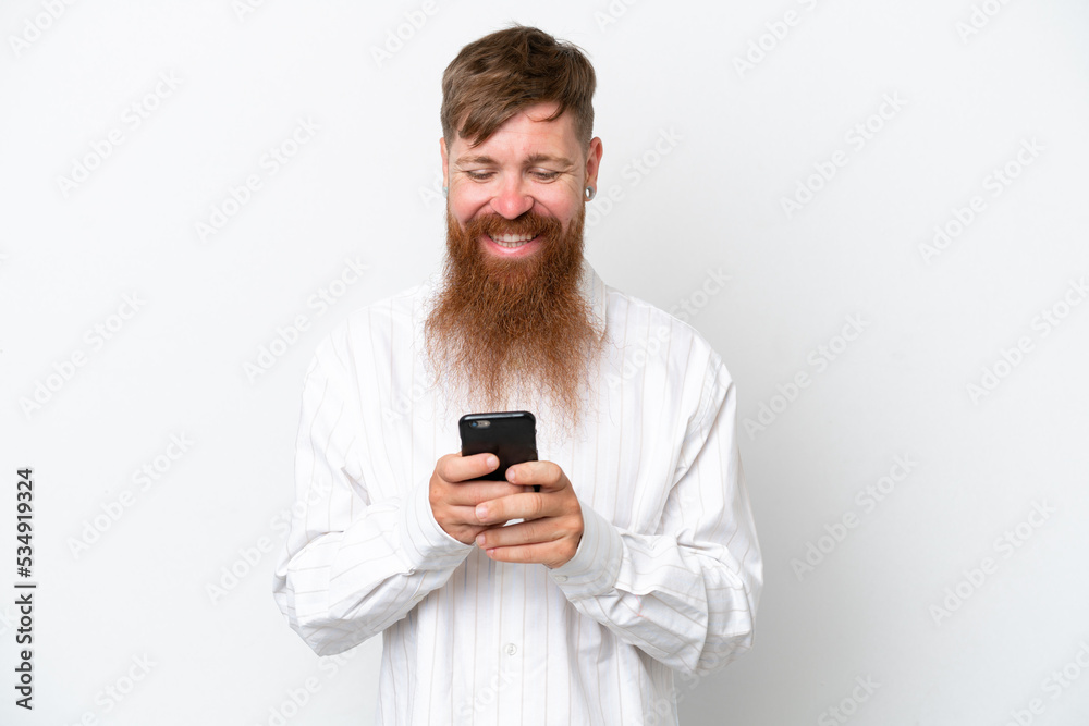 Redhead man with long beard isolated on white background sending a message with the mobile Redhead man with long beard isolated on white background sending a message with the mobile