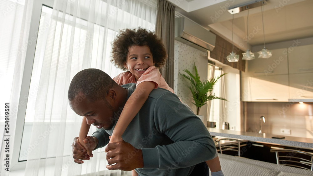 © Svitlana - Father carrying his little son piggyback at home