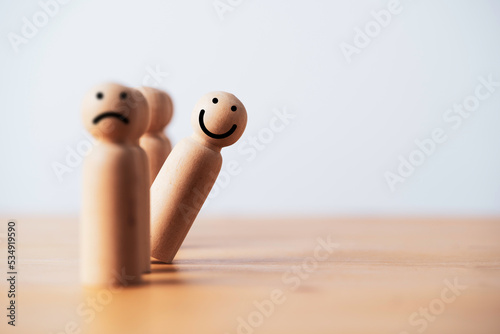smile face on wooden figure out of line from sad face with copy space for positive mindset selection concept. photo