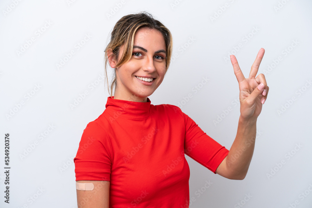 Young caucasian woman wearing band-aids isolated on white background smiling and showing victory sign Young caucasian woman wearing band-aids isolated on white background smiling and showing victory sign