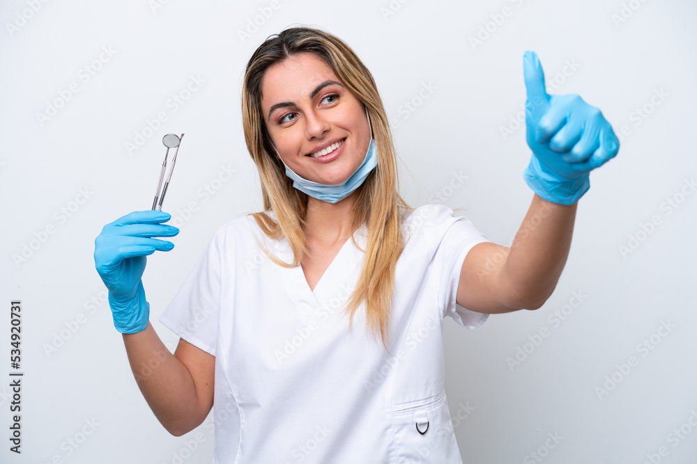 Dentist woman holding tools isolated on white background giving a thumbs up gesture Dentist woman holding tools isolated on white background giving a thumbs up gesture