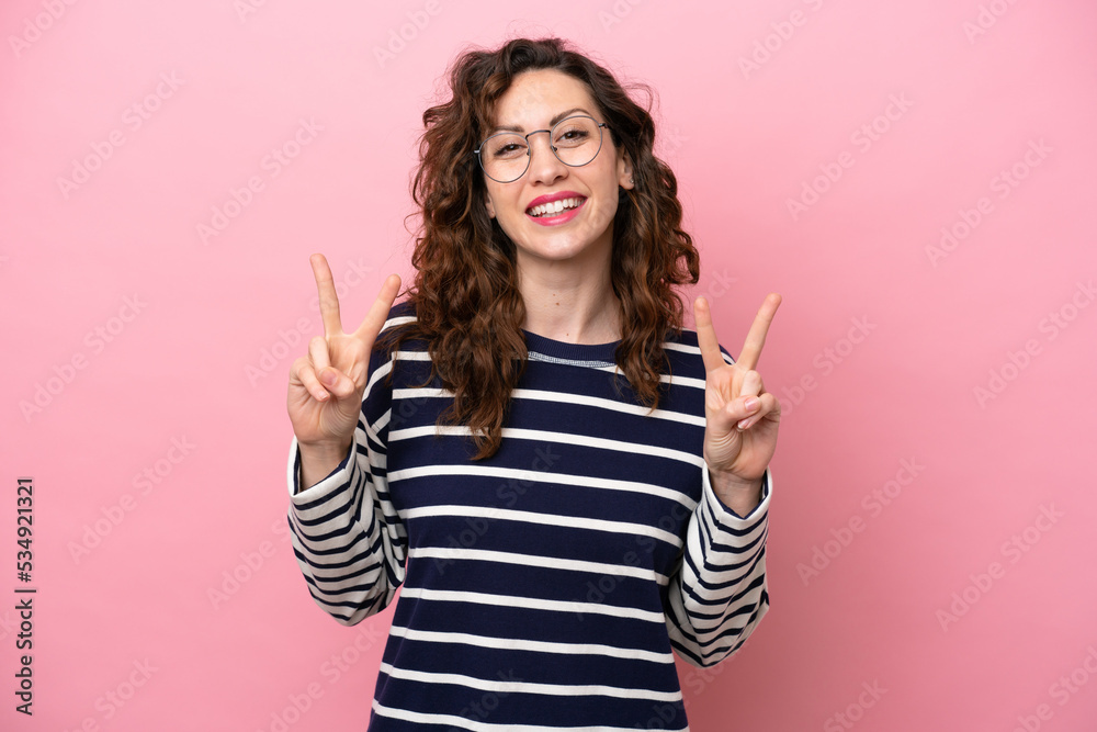 Young caucasian woman isolated on pink background showing victory sign with both hands