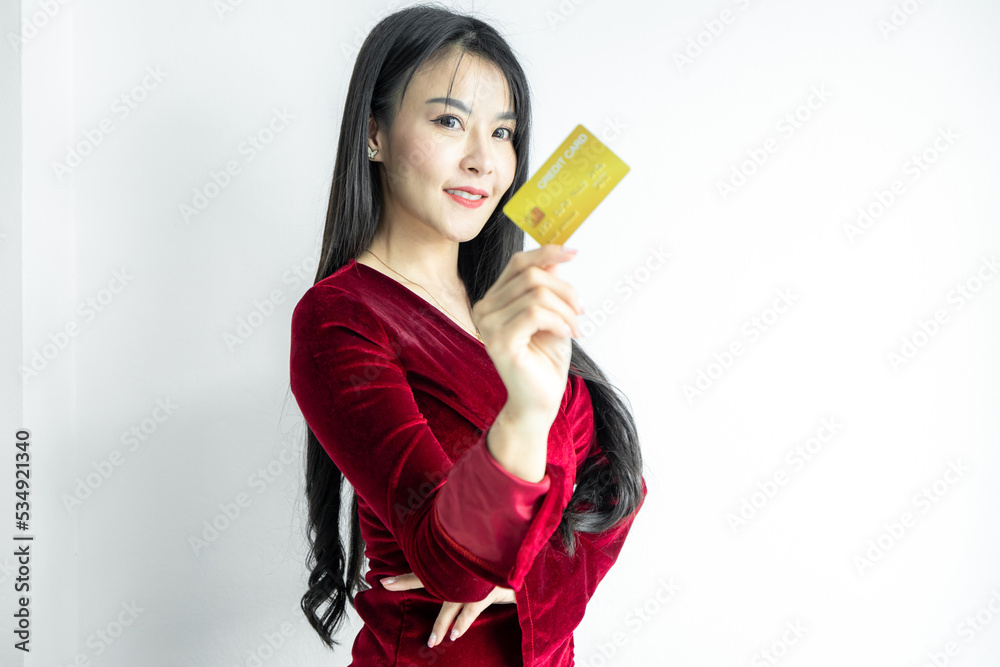 Beautiful Asian woman in red dress holding credit card on white background, Asian woman smiling showing presenting credit card, Woman holding bank business credit card, copy space. Beautiful Asian woman in red dress holding credit card on white background, Asian woman smiling showing presenting credit card, Woman holding bank business credit card, copy space.