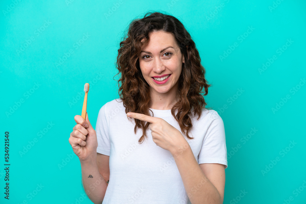 Young caucasian woman brushing teeth isolated on blue background and pointing it Young caucasian woman brushing teeth isolated on blue background and pointing it