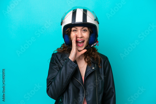 Young caucasian woman with a motorcycle helmet isolated on blue background shouting with mouth wide open