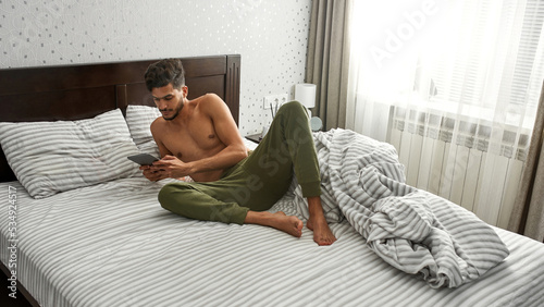 Middle eastern man watching digital tablet on bed