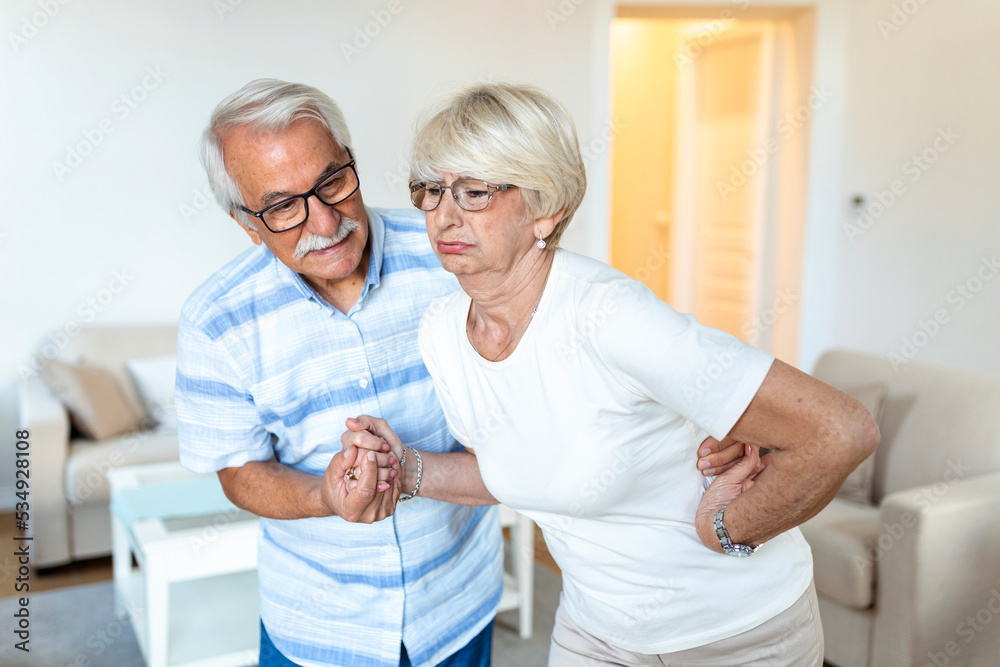 Senior couple at home. old woman is having back pain and her attractive old husband supports her. Senior couple at home. old woman is having back pain and her attractive old husband supports her.