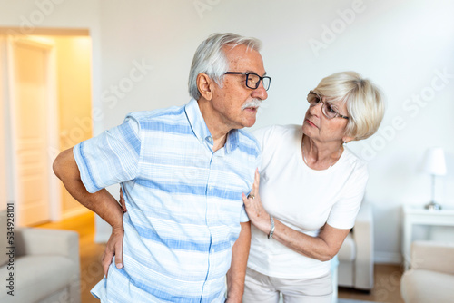 Senior couple at home.Elderly man is having back pain and his lovley wife supports him. photo