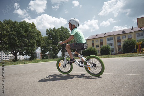 An active European child, a 9-year-old boy in protective gear for cyclists, in a sports helmet, rides a bicycle on an asphalt road on a sunny summer day. Active and healthy lifestyle concept
