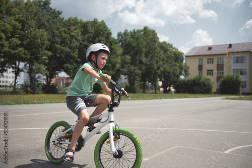 Active sporty 10 years old European boy in sports helmet confidently riding bike. Caucasian school age child cycling on the city asphalt road. Healthy lifestyle. Physical exercises. Motion. Extreme