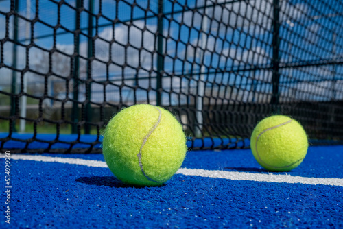 two balls near the net of a paddle tennis court, racket sports © Vic