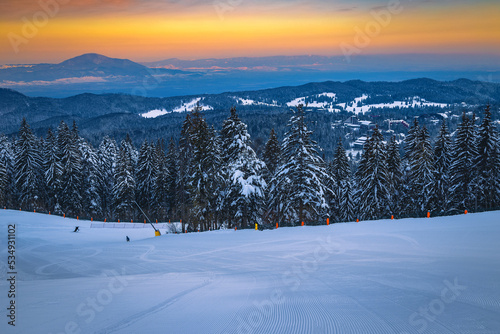 Wide ski slope in the snowy forest at sunrise, Romania
