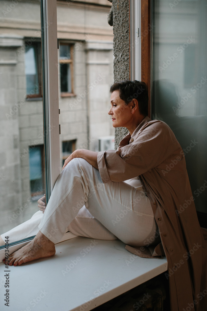 Portrait of beautiful mature woman relaxing by the window - stock photo Portrait of beautiful mature woman relaxing by the window - stock photo