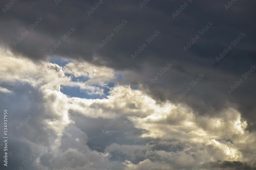 Picturesque thunder sky with cumulus clouds. Stormy sky with big clouds, backlit by sun. Air clouds background. Copy space. Selective focus. Picturesque thunder sky with cumulus clouds. Stormy sky with big clouds, backlit by sun. Air clouds background. Copy space. Selective focus.